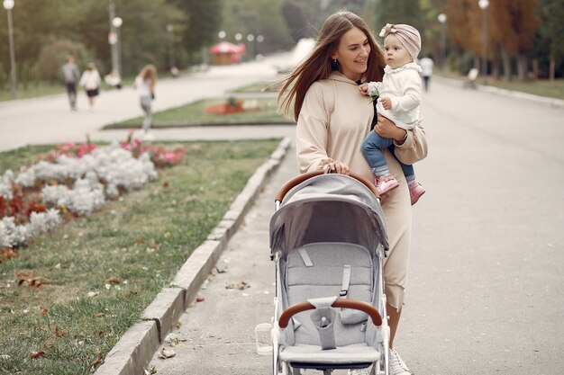 Joven madre caminando en un parque de otoño con carro