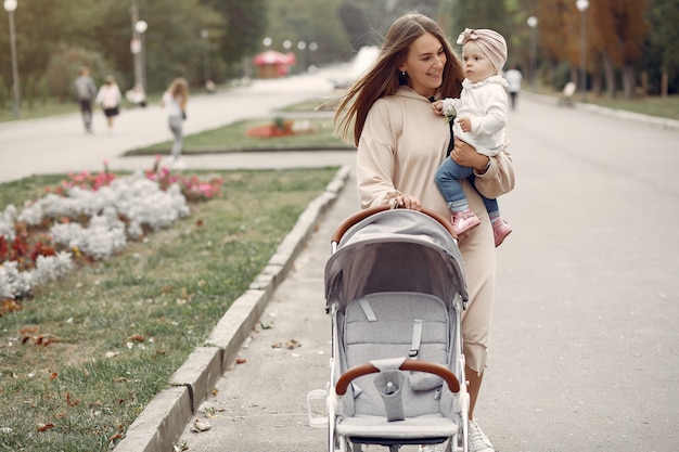 Joven madre caminando en un parque de otoño con carro