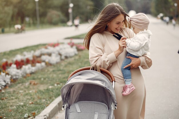 Joven madre caminando en un parque de otoño con carro