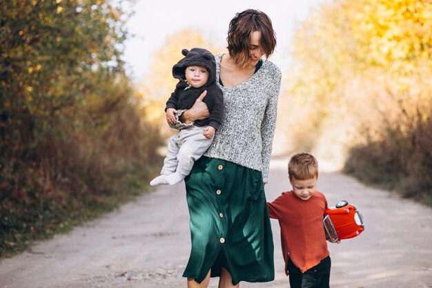 Joven madre con dos hijos caminando en el parque