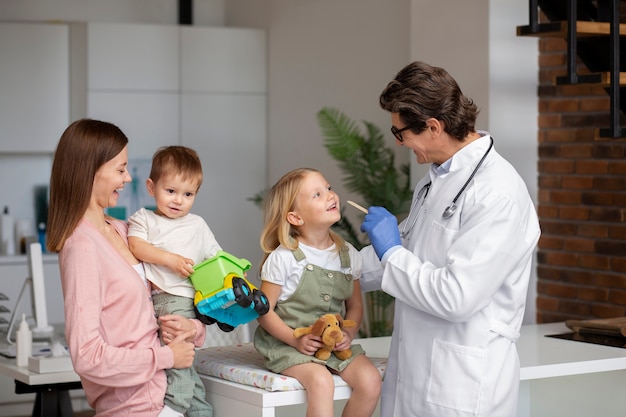 Foto gratuita joven madre con dos hijos en una cita con el médico