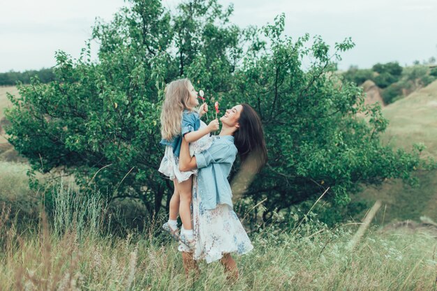 La joven madre e hija sobre la hierba verde