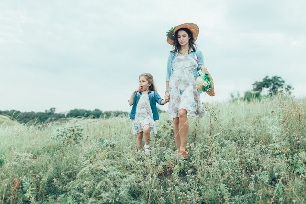 La joven madre e hija sobre la hierba verde