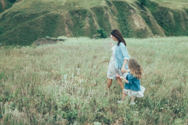 La joven madre e hija sobre la hierba verde