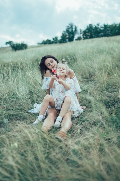 La joven madre e hija sobre la hierba verde