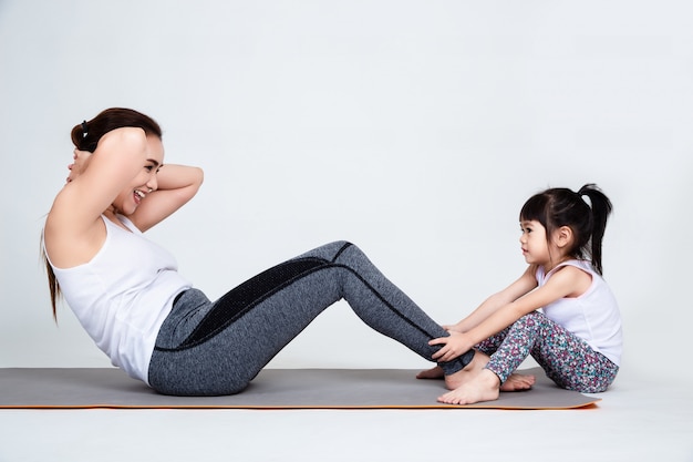 Joven madre entrenando encantadora hija con gimnasia