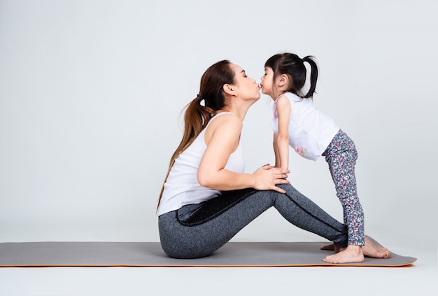 Joven madre entrenando encantadora hija con gimnasia