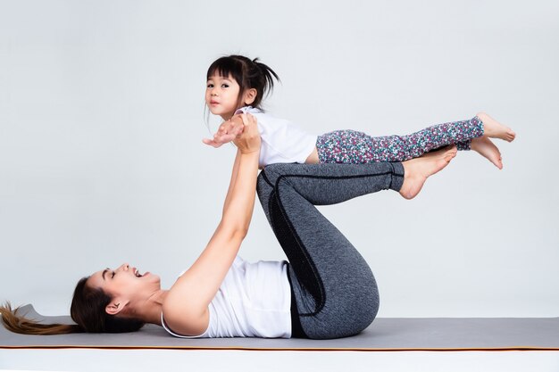 Joven madre entrenando encantadora hija con gimnasia