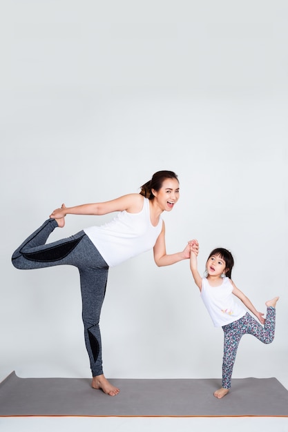 Joven madre entrenando encantadora hija con gimnasia