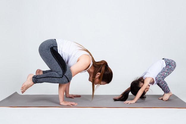 Joven madre entrenando encantadora hija con yoga