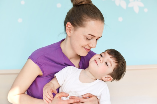 Joven madre europea adorable abraza hijo tener alegría juntos