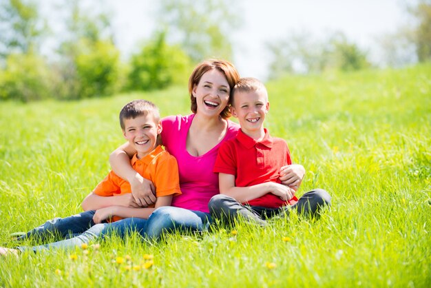 Joven madre feliz con niños en el parque - retrato al aire libre
