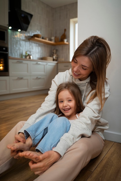 Foto gratuita joven madre haciendo reír a su hija haciéndole cosquillas