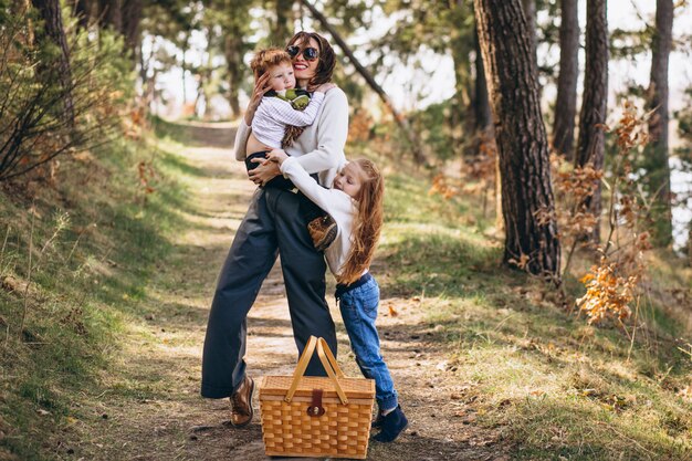 Joven madre con hija e hijo caminando para picnic en el bosque