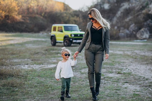 Joven madre con hija linda en el parque en coche