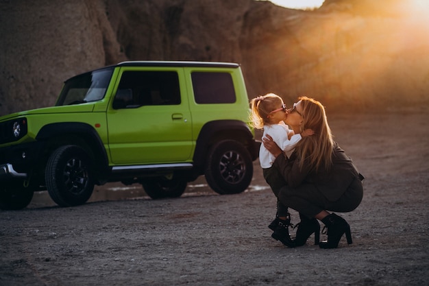 Joven madre con hija linda en el parque en coche