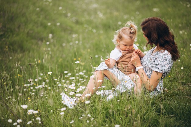 Joven madre con hija pequeña en el parque sentado en el césped