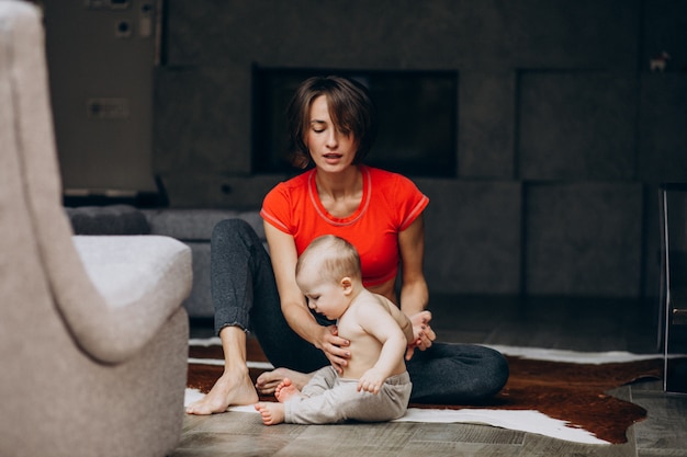 Joven madre con hijo pequeño practicando yoga en casa