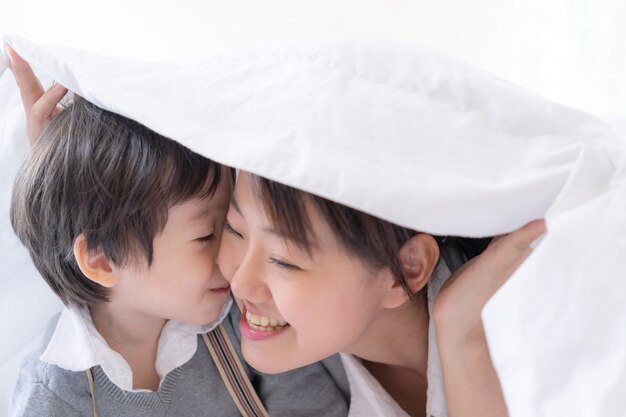 Joven madre y niño bajo una manta con felicidad