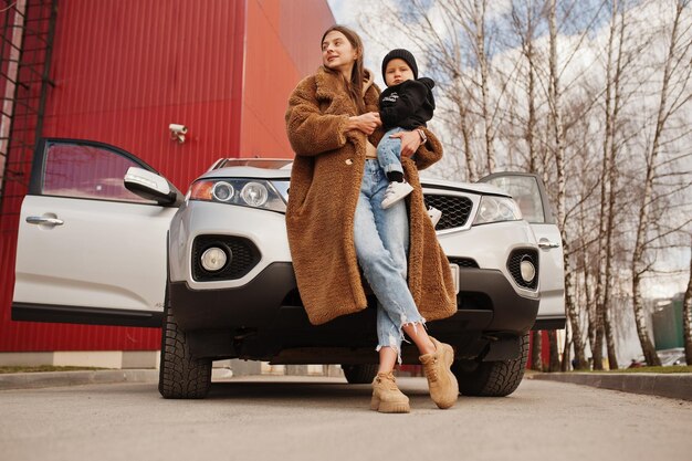 La joven madre y el niño se paran cerca del automóvil todoterreno Concepto de conducción segura