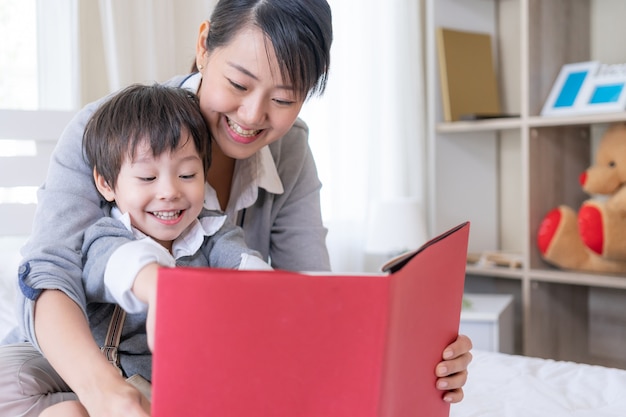 Joven madre y pequeño hijo leyendo libro en casa