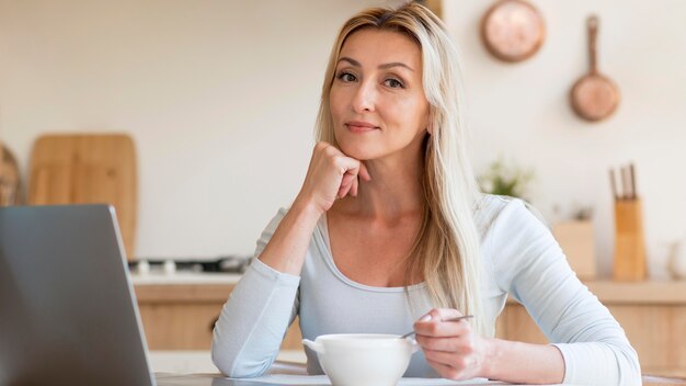 Foto gratuita joven madre posando mientras trabaja y desayuna en casa