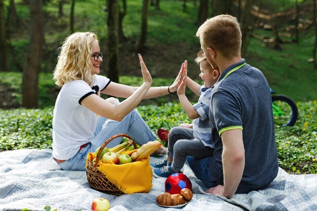 Joven madre rubia juega con su hijo durante un picnic en el parque