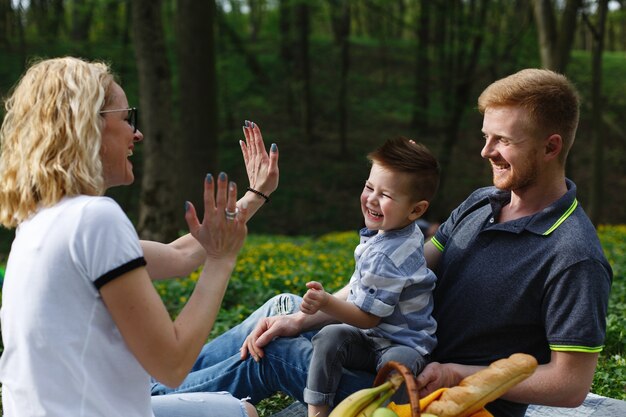 Joven madre rubia juega con su hijo durante un picnic en el parque