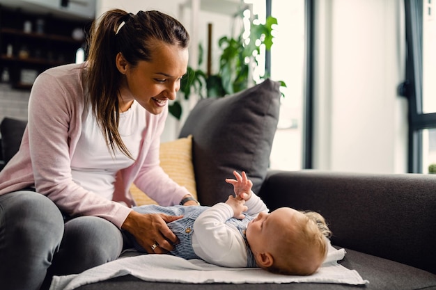 Joven madre sonriente disfrutando del tiempo que pasa con su bebé en casa