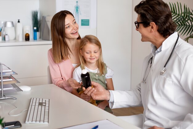 Joven madre con su hija en el pediatra para una consulta.