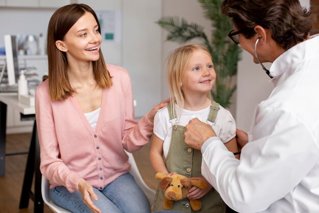 Joven madre con su hija en el pediatra para una consulta.