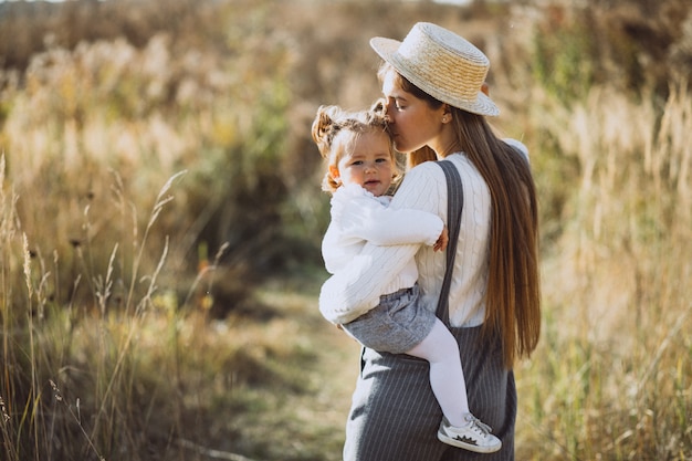 Joven madre con su pequeña hija en un campo de otoño