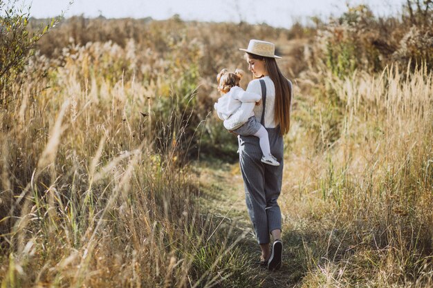 Joven madre con su pequeña hija en un campo de otoño