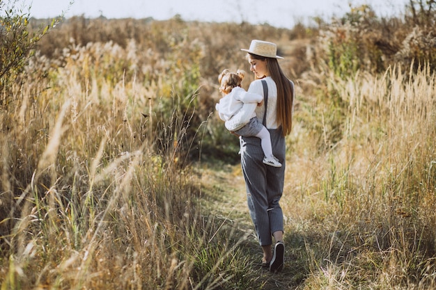 Joven madre con su pequeña hija en un campo de otoño