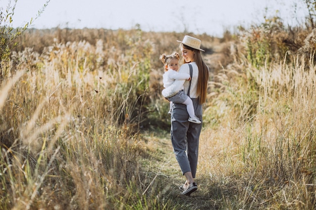 Joven madre con su pequeña hija en un campo de otoño