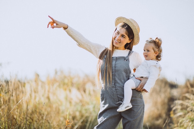 Joven madre con su pequeña hija en un campo de otoño