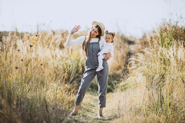 Joven madre con su pequeña hija en un campo de otoño