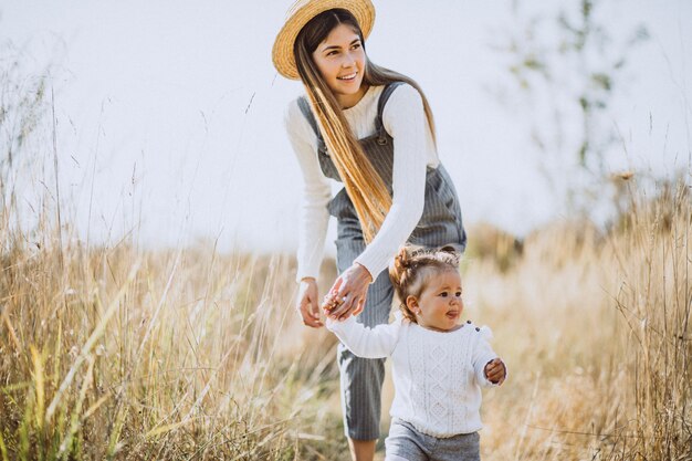 Joven madre con su pequeña hija en un campo de otoño