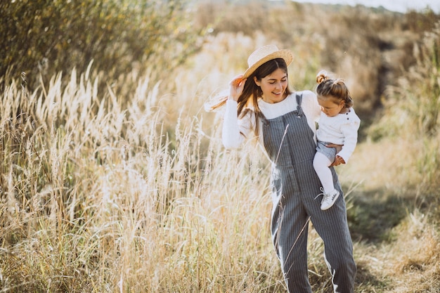 Joven madre con su pequeña hija en un campo de otoño