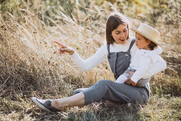 Joven madre con su pequeña hija en un campo de otoño