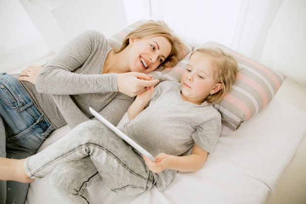 Joven madre y su pequeña hija en casa por la mañana soleada. Colores pastel suaves. Tiempo en familia feliz el fin de semana. Concepto del día de la madre. Conceptos de familia, amor, estilo de vida, maternidad y momentos tiernos.