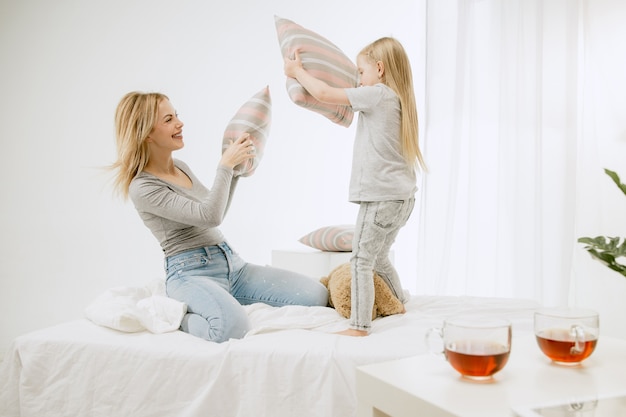 Joven madre y su pequeña hija en casa en la mañana soleada. Colores pastel suaves. Tiempo en familia feliz el fin de semana.