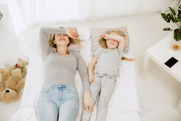 Joven madre y su pequeña hija en casa en la mañana soleada.