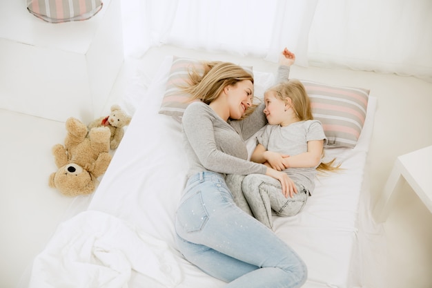 Joven madre y su pequeña hija en casa en la mañana soleada.