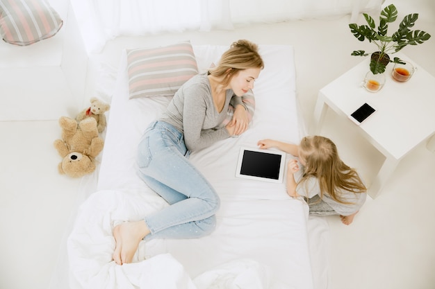 Joven madre y su pequeña hija en casa en la mañana soleada.