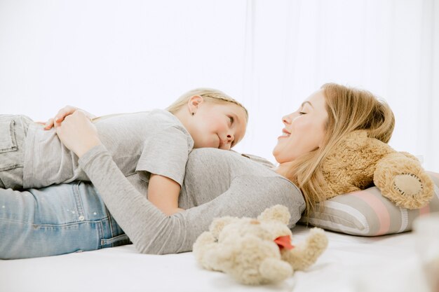 Joven madre y su pequeña hija en casa en la mañana soleada.