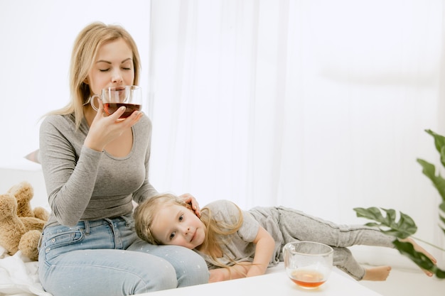 Joven madre y su pequeña hija en casa en la mañana soleada.