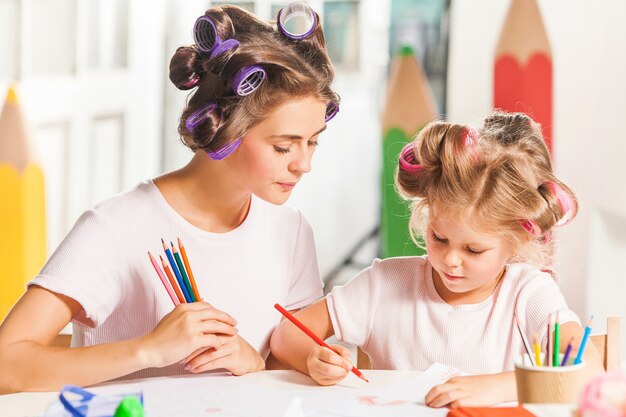 Foto gratuita joven madre y su pequeña hija dibujando con lápices en casa