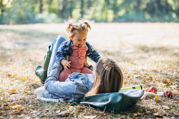 Joven madre con su pequeña hija en un parque de otoño con picnic