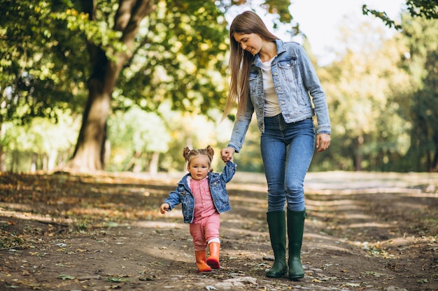 Joven madre con su pequeña hija en un parque de otoño